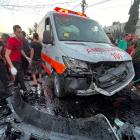 Palestinians check the damage after a convoy of ambulances was hit, at the entrance of Shifa...