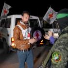 A Hamas militant interacts with Red Cross members as hostages are handed over at an unknown...