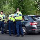 Police confer outside an unmarked police car at the scene of a single-vehicle crash in Neill St,...