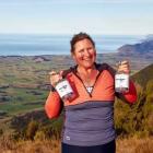 Justine Schroder standing on Mt Fyffe with her award winning gins. Photo: Supplied

