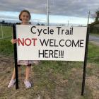 Poppy Sutherland, 10, stands by a sign at the entrance of her home opposing the route of a...