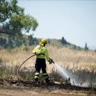 A firefighter dampens down a small vegetation fire next to State Highway 85, near Springvale on...