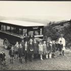 Children and their driver stand in front of a Peninsula Motor Service bus on the Leith Saddle on...