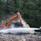 Firefighters dampen down hot spots at the Cromwell transfer station yesterday after a fire...