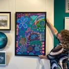 Otago Art Society publicity officer Jenny Longstaff adjusts a work in the popular "Love, Buy,...