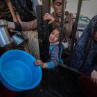 Displaced Palestinians wait to receive food cooked by a charity kitchen amid shortages of food...