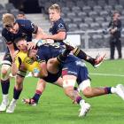 Highlanders forwards Max Hicks (right) and Fabian Holland clear out Hurricanes halfback Cam...