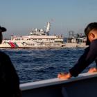 Members of the Philippine Coast Guard stand alert as a Chinese Coast Guard vessel blocks their...