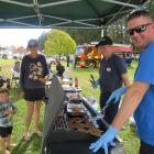 Attendees, pictured at left, enjoy a sausage in a blanket from barbecue masters Owen Wylie, left,...