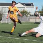 Universities defender Max McGuinness makes a clearance under pressure from Christchurch United's...