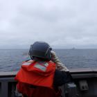 A Taiwanese sailor aboard a Taiwan Navy vessel looks towards a Chinese warship while navigating...
