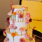 The three-tier wedding cake, made by Blue Poppy Cake Design, was decorated with bright florals to...