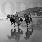 Three young riders are mirrored in the wet sand as they gallop along the beach at St Clair on a...