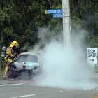Firefighters work to extinguish the car fire. Photo: Gregor Richardson