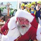 Santa Claus gives a festive wave, backed by some of the 80 floats that travelled down George St...