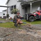 Beaumont resident Jamie Benington pumps floodwater from underneath his home after a river of...