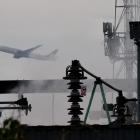 A plane takes off, as smoke rises from an area of an electrical substation a day after it caught...