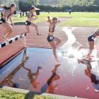 Rising stars clear the hurdle and run through the water during the women's under-18 steeplechase...
