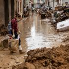 A woman walks through mud in the street after heavy rain and flooding hit large parts of Valencia...