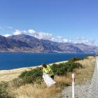 A road worker has a picturesque backdrop of Lake Wanaka while working on picking up rubbish off...