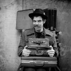 Suitcase Show co-creator Ralph McCubbin Howell holds a variety of suitcases, each containing a...