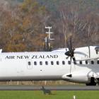 An Air New Zealand ATR-72 turboprop plane taxis past a wooden coyote silhouette at Dunedin...