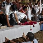 Relatives of one of the crash victims lower a coffin containing his remains into a grave at a...