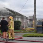 Firefighters extinguish a house fire in Gore yesterday afternoon. PHOTO: STEPHEN JAQUIERY
