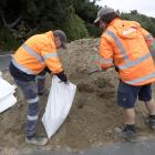 Delta employees Peter Soper (left) and Simon Smaill fill a sandbag at the Dunedin Ice Stadium...