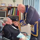 Junior grand warden Paul Johnston pins a 60-year service bar on to past master Owen Soal. PHOTO:...