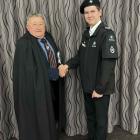 St John Youth cadet corporal Corey Miller (right), shaking hands with Doug Dance, a Commander of...