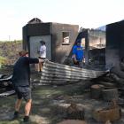 Locals clean up after a fire on Harnetts Rd, north of Kaikoura, this week. Photo: Biddy Getz