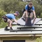 Installing solar panels on the roof of a Port Chalmers property are Dunedin Solar installers Grey...