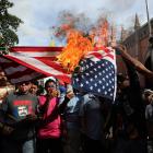 Venezuelan residents burn the United States flag to protest the seizing of President Nicolas...