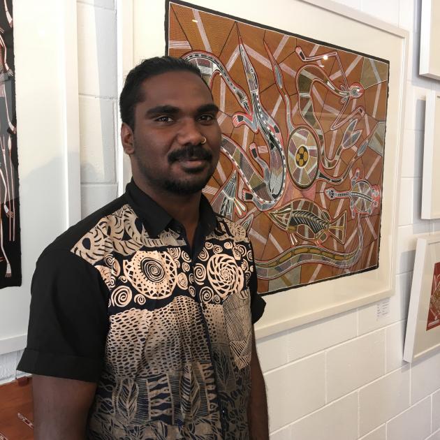 Artist Rodriguez Wilson is flanked by some of his artworks at Provenance Arts, in Darwin. The...