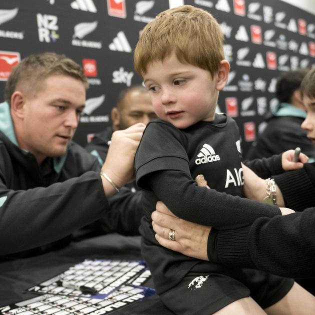Highlanders and All Blacks prop Ethan de Groot signs the back of 3-year-old Levi Barsley. PHOTO:...