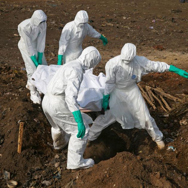 Health workers carry the body of a suspected Ebola victim for burial at a cemetery in Freetown, Sierra Leone, in 2014. Better links are needed to ensure good responses in a crisis, the writer argues. Photo from Reuters.