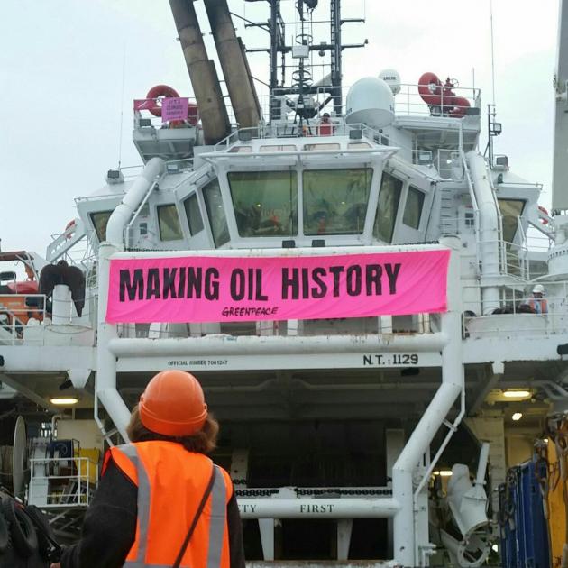 An environmental protester stands on the deck of offshore supply vessel Skandi Atlantic in front...