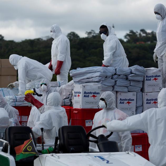 Airport staff and Royal Australian Air Force personnel move humanitarian aid packages at Port...