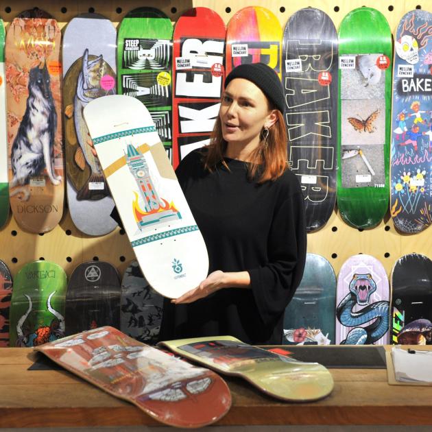 Evie Forno shows off a skateboard painted by Sean Duffel as part of the store’s local artist...