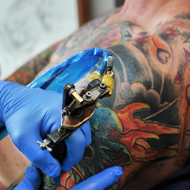 Chris Downing works away at a tattoo on customer Chris Dick’s arm. PHOTO: CHRISTINE O’CONNOR