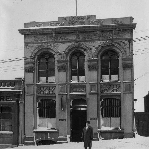 An unidentified person stands in the snow in front of the Sew Hoy building in Dunedin in the late...