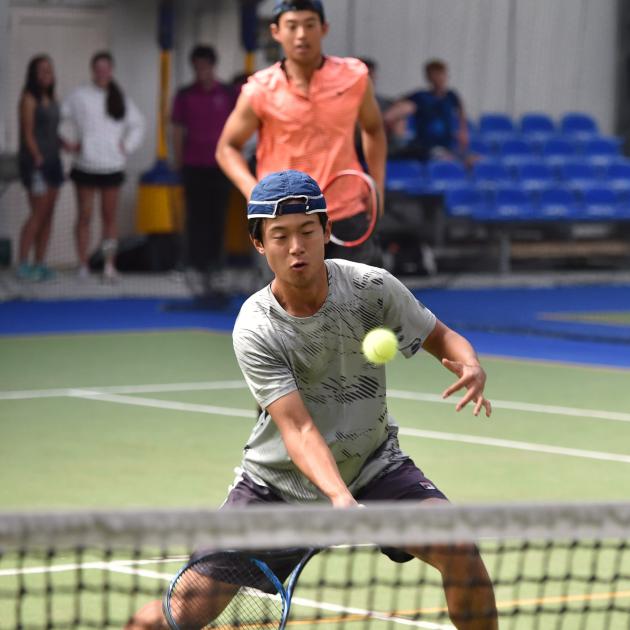 Thomas Hartono volleys the ball, watched by his doubles partner and brother Peter Hartono, at the...