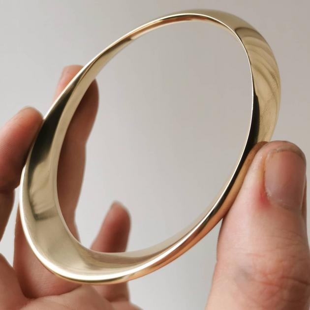 Oval Bangle, crafted from solid 9ct gold is a custom-made piece; refined lines reflect a minimal...