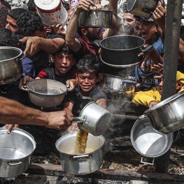 Hungry Palestinians wait to receive meals distributed by charity organisation in Jabalia Refugee...