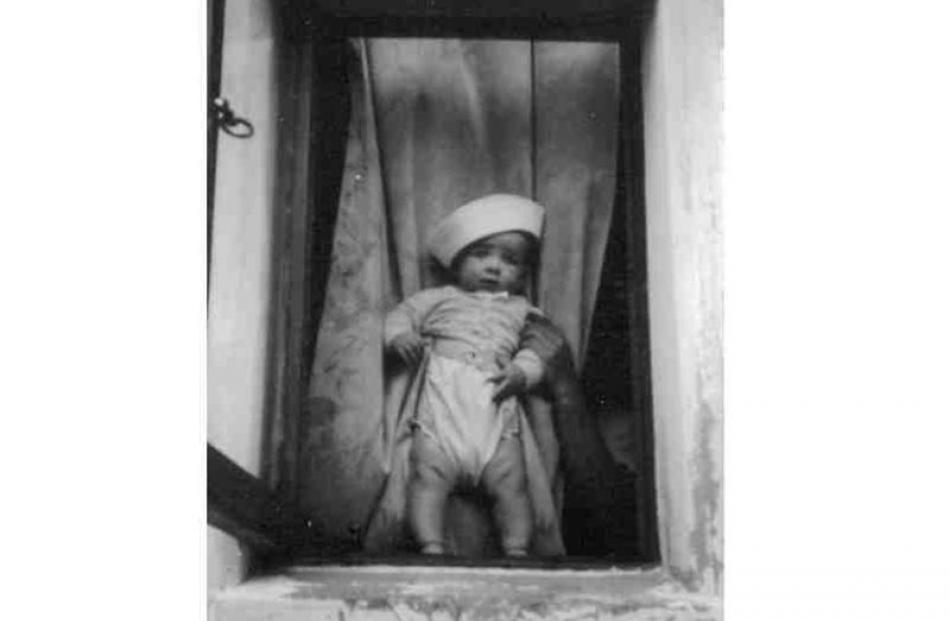 Wearing a sailor hat, baby Earl is framed by the lounge window. Photo supplied.