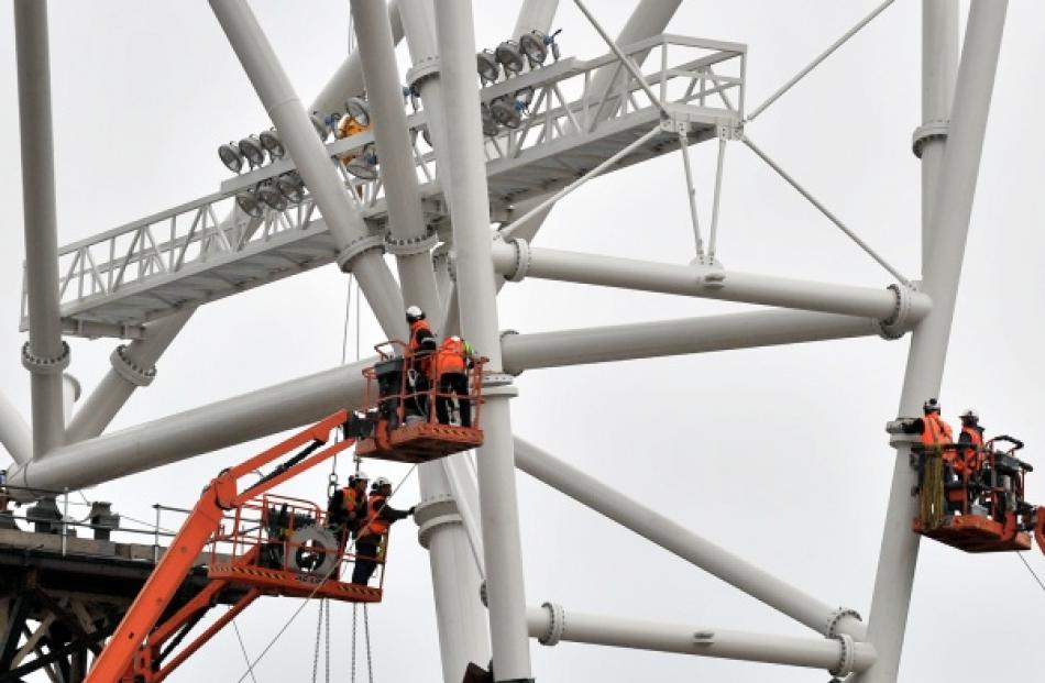 Contractors attach a piece of steel truss to a support column at the stadium site yesterday.