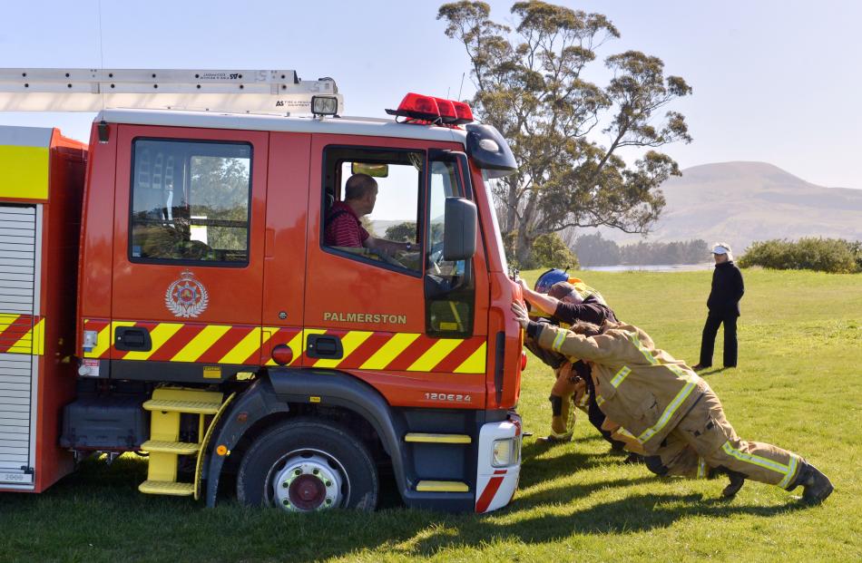 Firefighters try to free the Palmerston volunteer brigade fire engine after it became stuck while attending an accident at Karitane in which a car ended up down a bank yesterday morning. Photos by Gerard O'Brien.