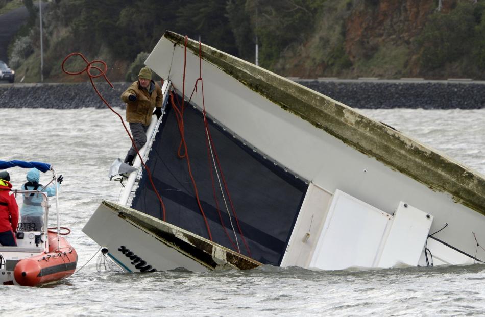 The owner and builder of a catamaran capsized at Macandrew Bay throws a line to an inflatable...