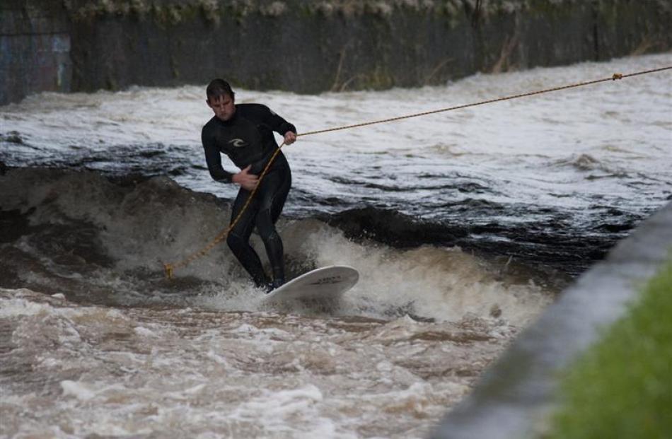 Surfers ride the current on the swollen Leith yesterday afternoon. Photo by Max Bellamy.